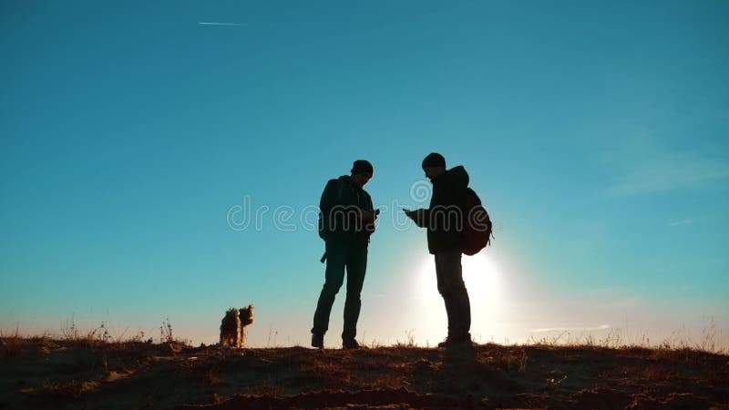 teamwork zwei Touristenwanderermänner und -hund mit Rucksäcken bei Sonnenuntergang gehen, Reise zu wandern Zeitlupevideo Smartpho