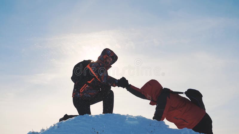 teamwork Zwei touristische Wanderer gibt eine Handreichung Erfolgsgewinnwinter erreichte die Spitze des Berges Touristenbergsteig