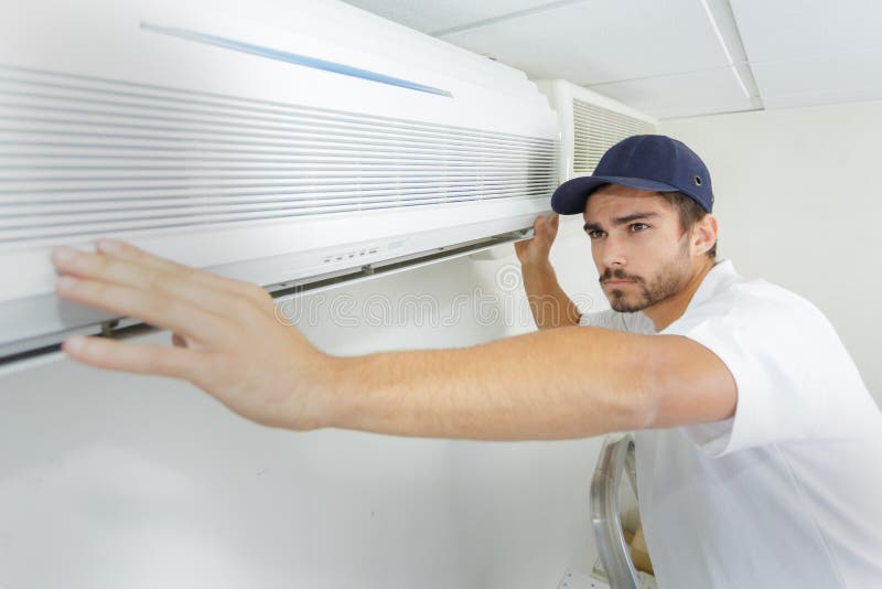 Tech guy carefully installing new ac office. Tech guy carefully installing new ac office