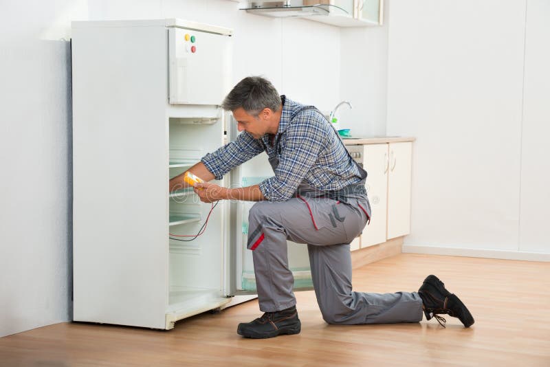 Technician Checking Fridge With Digital Multimeter royalty free stock image