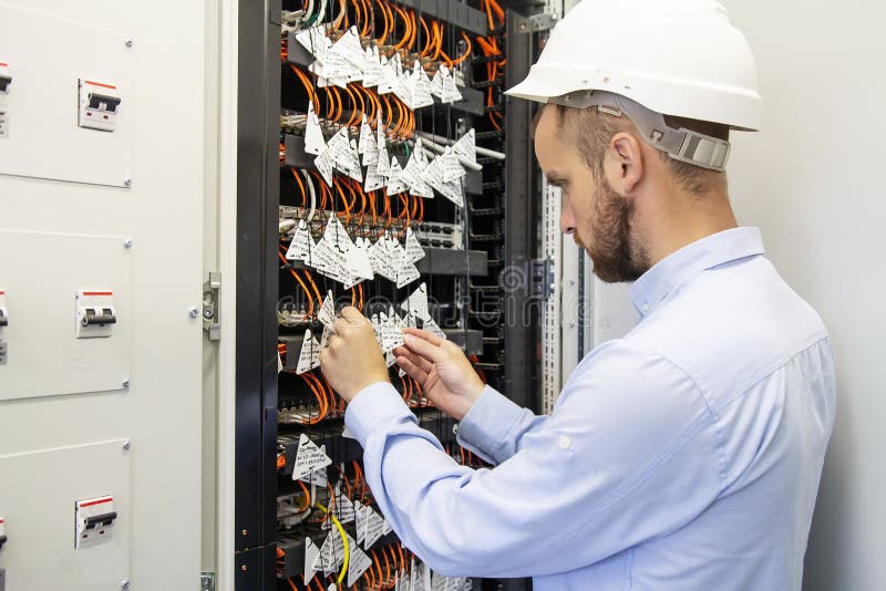 Technician engineer connects optical fibers into communication switch in data center. Service man in datacenter royalty free stock photography