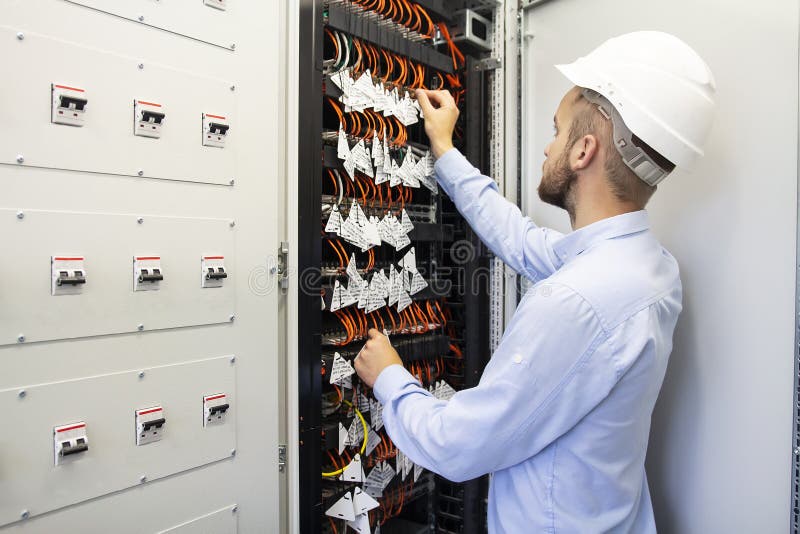 Technician engineer in datacenter. Network technician connecting fiber optic at server room. royalty free stock image