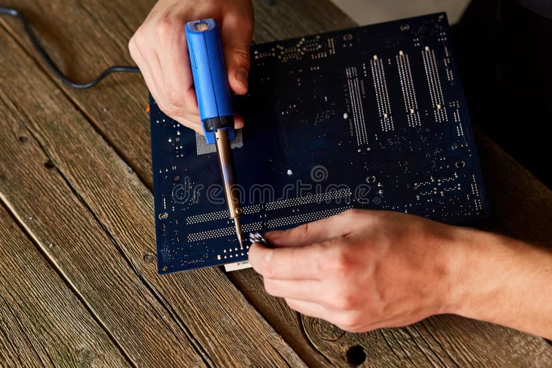 Technician or Engineer is Focused on Repairing Circuit Board with