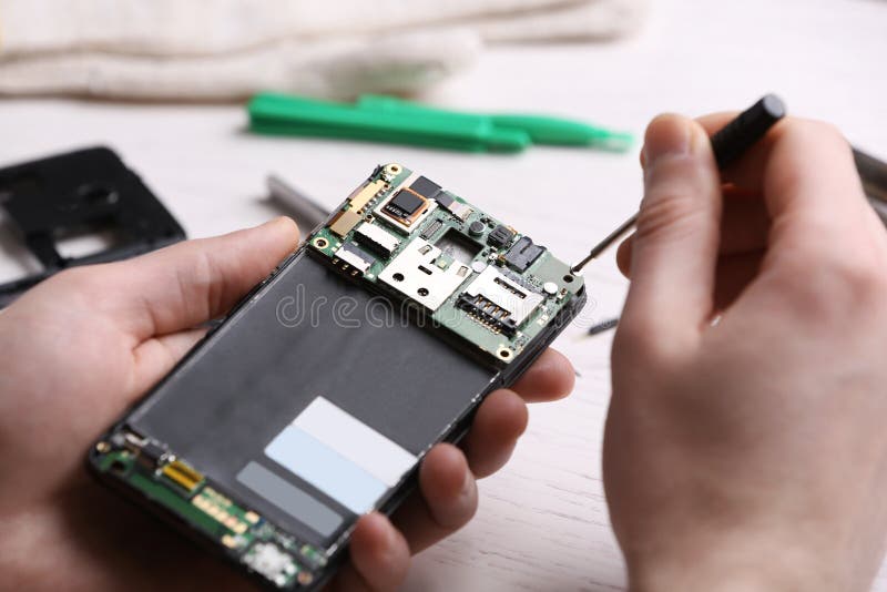 Technician Fixing Mobile Phone at Table. Device Repair Service Stock