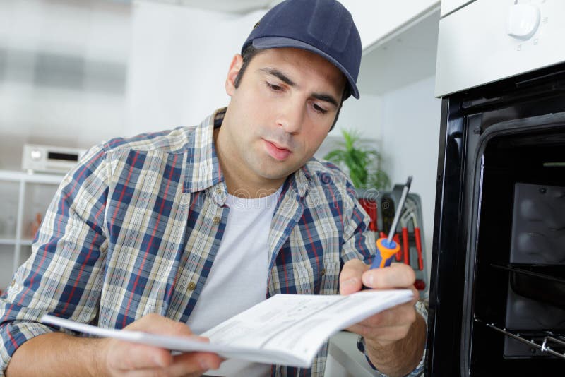 Technician with Home Appliances Reading Instructions Stock Photo