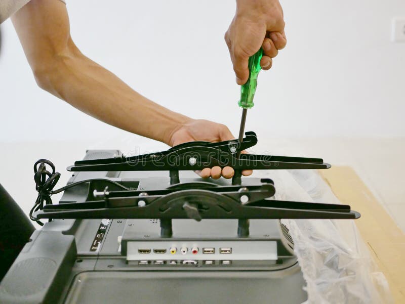 A Technician is Installing a Wall Mount on the Back of a Television