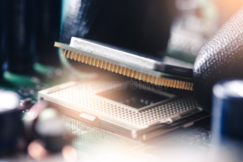 The technician is laying a CPU on the motherboard socket stock photo