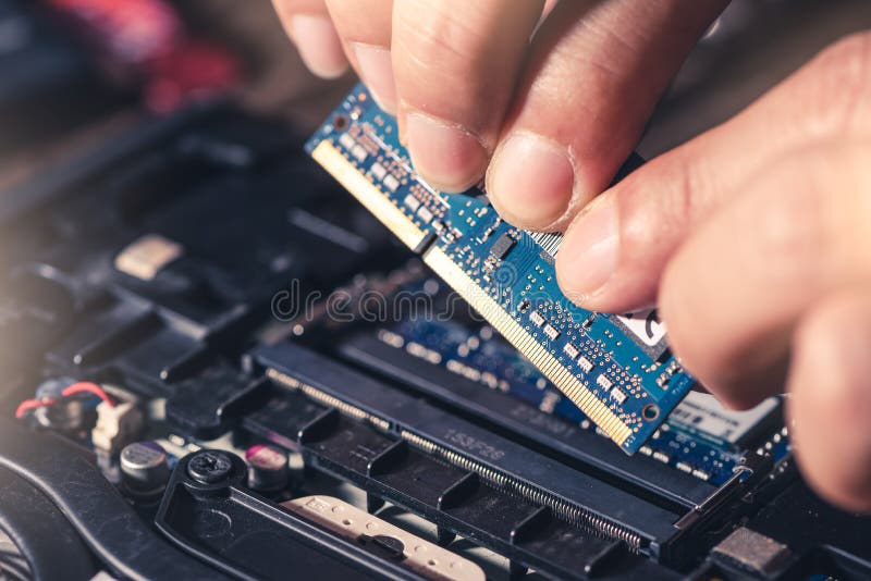 The technician is laying a RAM on the socket of the computer motherboard. stock photo