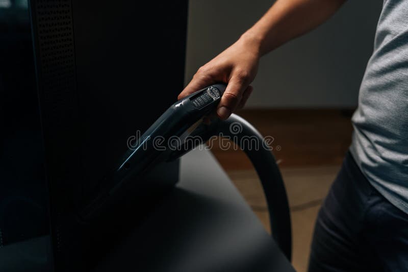 Technician male using vacuum cleaner to remove dust and debris from computer in repair shop, ensuring proper functioning stock photo