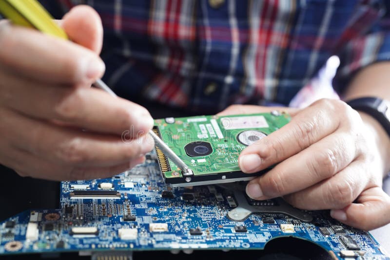 Technician Repairing Inside of Hard Disk by Soldering Iron. Stock Photo