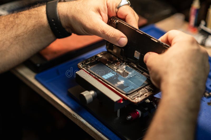 Technician repairing smartphone battery in workshop with tools and equipment during daytime stock photo