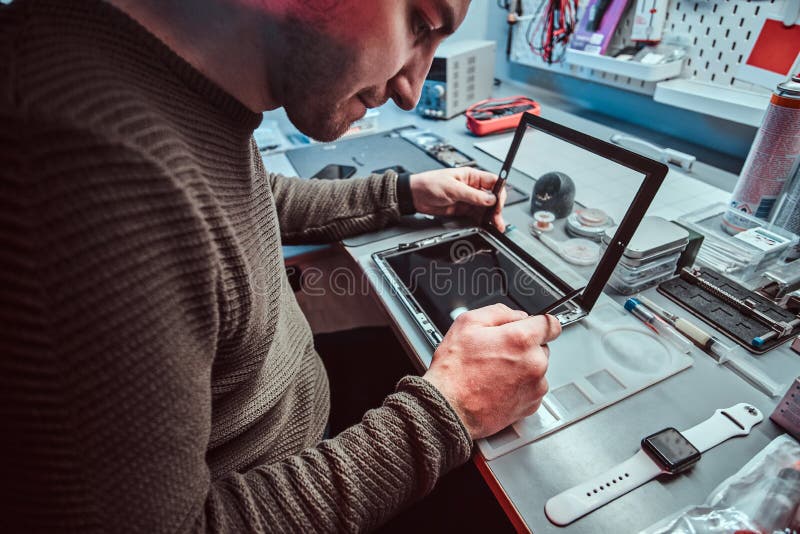 The Technician Repairs a Broken Tablet Computer in a Repair Shop