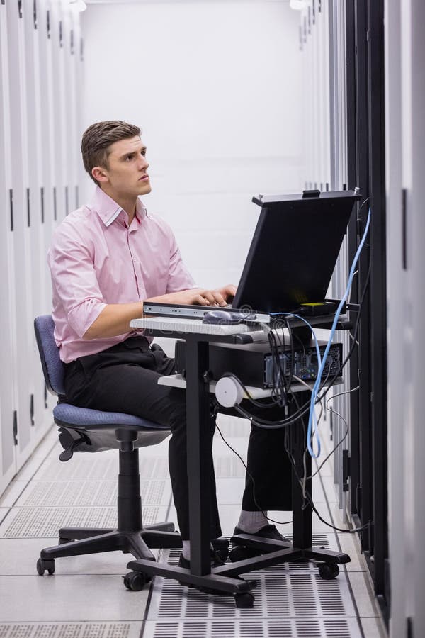Technician sitting on swivel chair using laptop to diagnose servers royalty free stock photos Technician sitting on swivel chair using laptop to diagnose servers royalty free stock photos