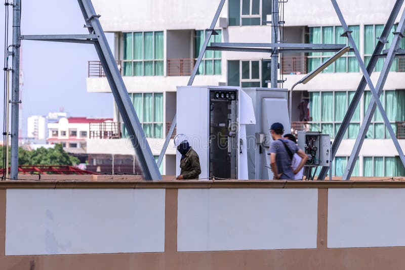 Technician support installing internet cable in controller box on the roof