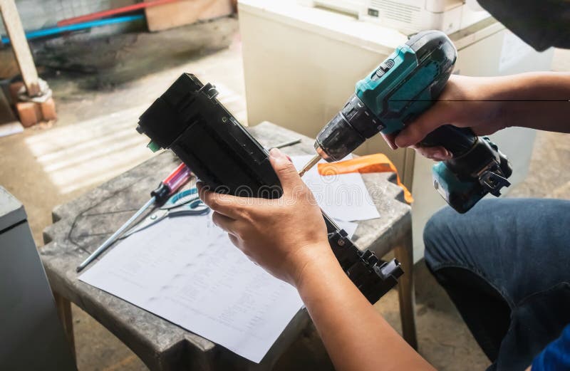 Technician is using an electric drill to tighten the drum`s nuts to disassemble it, repair it and clean it stock images