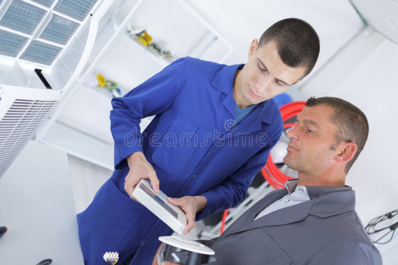 Technicians Operating Remote Control for Air Conditioning Unit Stock