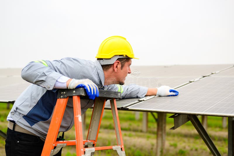 Technicien d'entretien vérifiant les panneaux solaires sur la ferme à cellules solaires image libre de droits