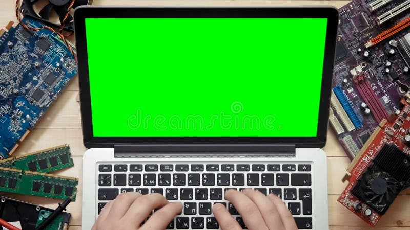 Technicien d'ordinateur de vue supérieure à l'aide de l'ordinateur portable avec l'écran vert au bureau en bois avec des outils e clips vidéos