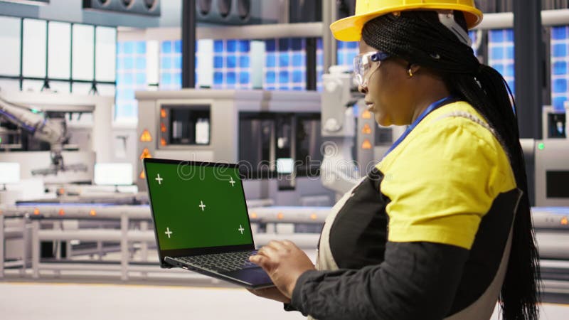 Technicien dans une usine industrielle utilisant un ordinateur portable à écran vert pour diagnostiquer l'équipement banque de vidéos