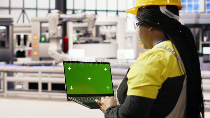 Technicien dans une usine industrielle utilisant un ordinateur portable à écran vert pour diagnostiquer l'équipement clips vidéos