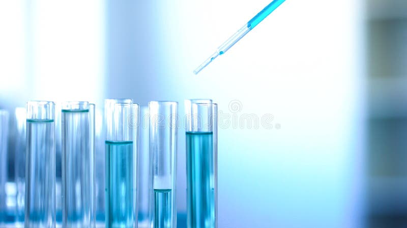 Technicien de laboratoire versant le liquide bleu dans des tubes, production détersive de nettoyage photo libre de droits Technicien de laboratoire versant le liquide bleu dans des tubes, production détersive de nettoyage photo libre de droits