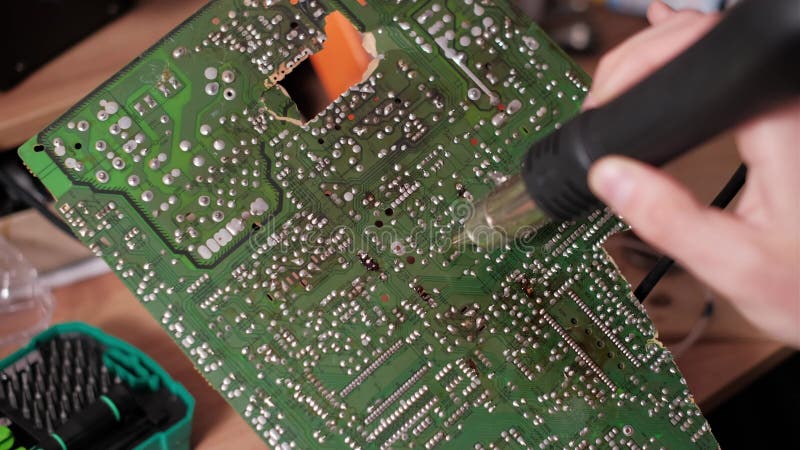 Technicien utilisant un pistolet à air chaud sur des joints de soudage à dos de PCB verts banque de vidéos