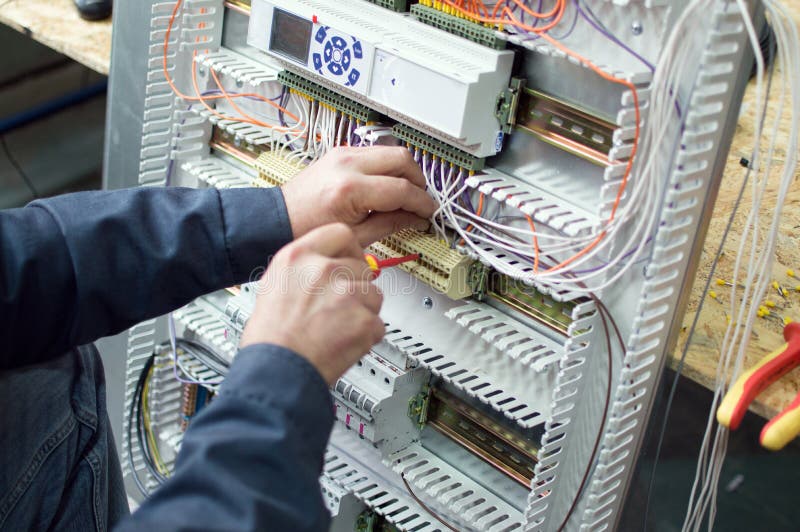 Technicus die laag voltage assembleren die industrieel HVAC-controlebord in workshop assembleren Close-upfoto van de handen stock afbeelding Technicus die laag voltage assembleren die industrieel HVAC-controlebord in workshop assembleren Close-upfoto van de handen stock afbeelding