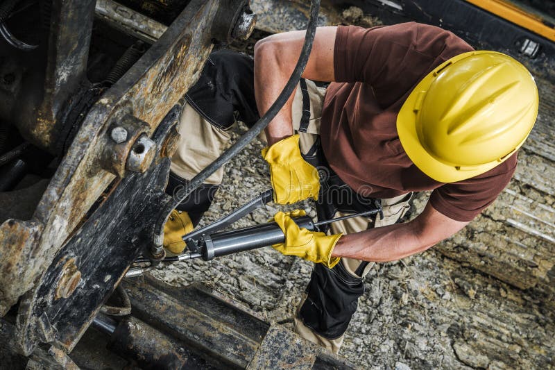 Heavy Duty Machinery Technician Pumping Grease Into Industrial Machine Using Hand Pump Gun. Top View. Heavy Duty Machinery Technician Pumping Grease Into Industrial Machine Using Hand Pump Gun. Top View