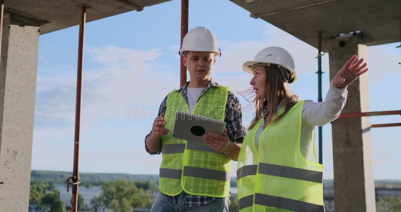 Technologie de la construction et concept de personnes - constructeurs de sourire dans des masques avec l'ordinateur de PC de com