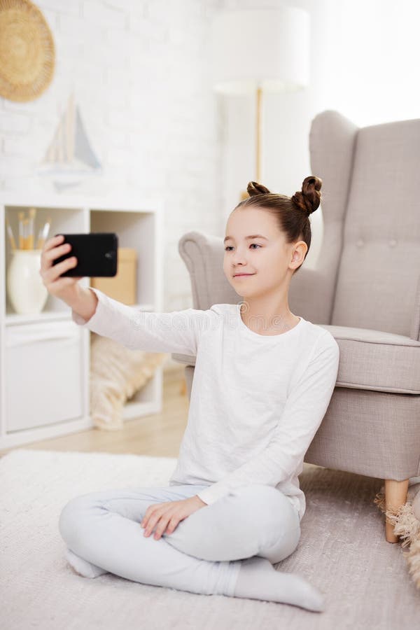 Technologie médias sociaux et internet concept mignon préadolescent fille prenant selfie photo avec smartphone à la maison photographie stock