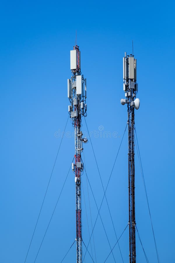 Technology of telecommunication GSM 5G,4G,3G tower. Cellular phone antennas on a building roof. Receiving and transmitting stations with blue skies on the background. Technology of telecommunication GSM 5G,4G,3G tower. Cellular phone antennas on a building roof. Receiving and transmitting stations with blue skies on the background.
