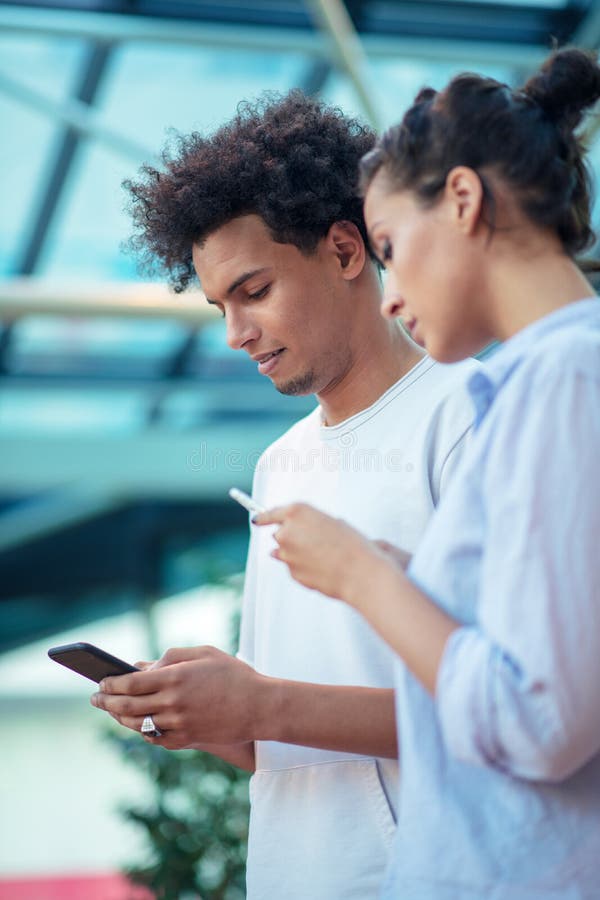 Tecnologia e viagem de Digitas Pares de amor novos no vestu?rio desportivo usando o smartphone ao estar no aeroporto fotografia de stock Tecnologia e viagem de Digitas Pares de amor novos no vestu?rio desportivo usando o smartphone ao estar no aeroporto fotografia de stock