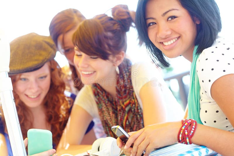 Technologically savvy. A group of adolescent girls laughing as they look at something on a smartphone screen. Technologically savvy. A group of adolescent girls laughing as they look at something on a smartphone screen