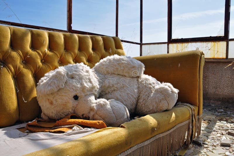 Teddy bear and couch in abandoned building