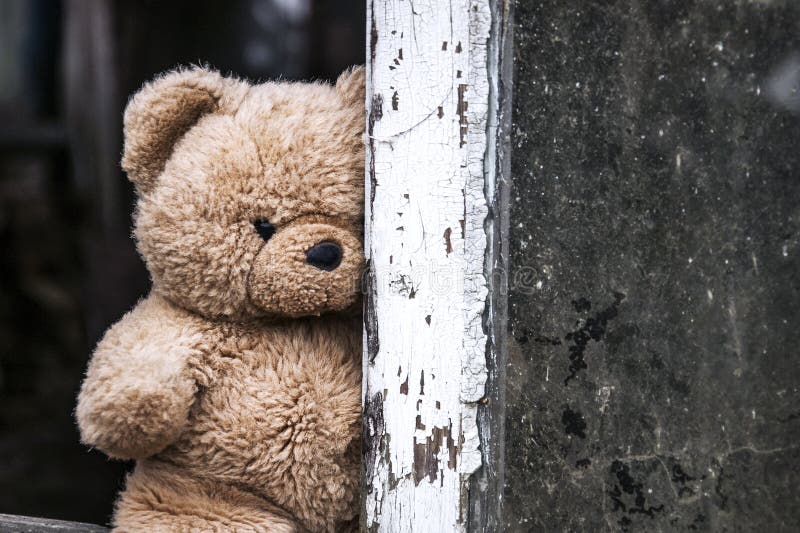 A teddy bear is looking at us from the window of an abandoned house.