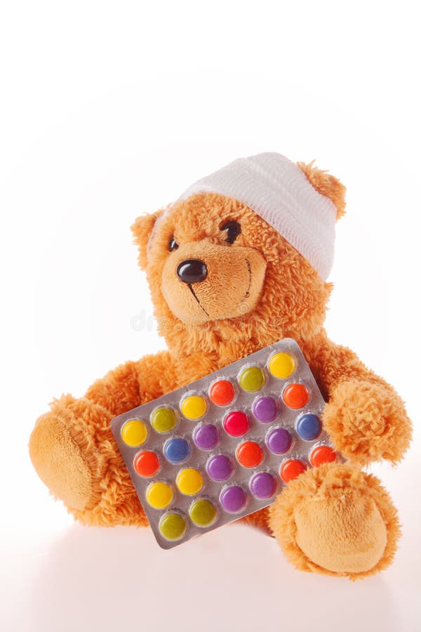 Teddy Bear met Verbandholding Gekleurde Pillen stock fotografie Teddy Bear met Verbandholding Gekleurde Pillen stock fotografie