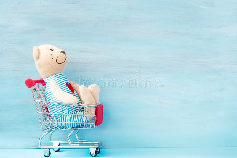 Teddy bear in shopping cart. Fast and free Delivery transport on blue backdrop. Online shopping and Express delivery