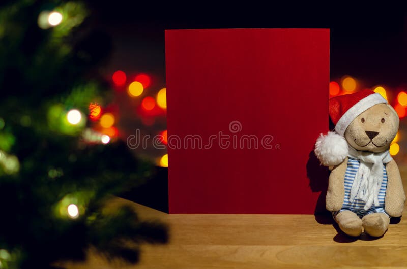Teddybär des Weihnachtsmanns sitzt neben leerer roter Karte