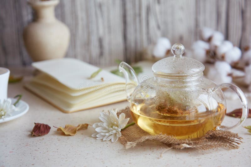 Tee aus ästhetischem Kräuterleinentee in Teekanne mit Tasse Tee. Weizenblätter aus Baumwolle Herbstdekorationen und Notizbuch. gem stockfotos