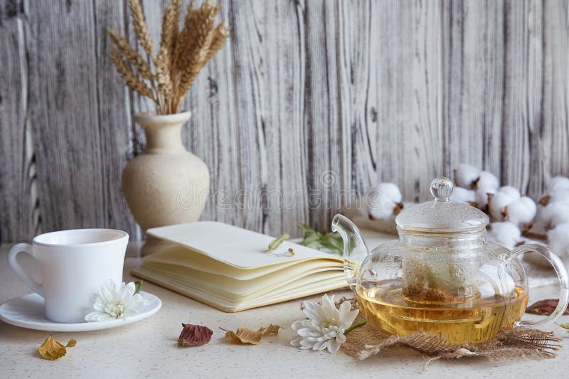 Tee aus ästhetischem Kräuterleinentee in Teekanne mit Tasse Tee. Weizenblätter aus Baumwolle Herbstdekorationen und Notizbuch. gem lizenzfreie stockbilder