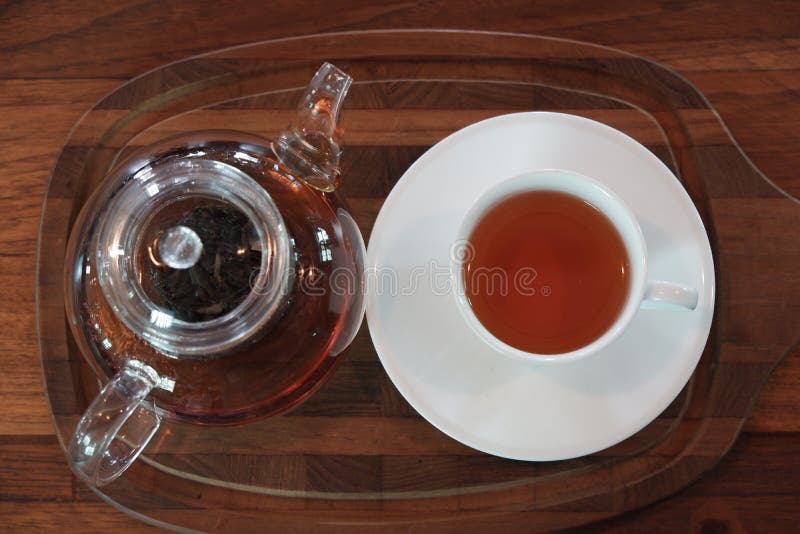 Tee Earl Grey im Glasteetopf auf h?lzerner Platte mit wei?er Schale lizenzfreie stockfotografie Tee Earl Grey im Glasteetopf auf h?lzerner Platte mit wei?er Schale lizenzfreie stockfotografie