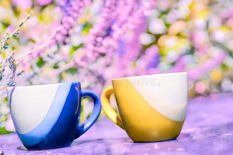 Coffee time.Break,pause and relax. Yellow and blue coffee tea cups on pink floral background. High quality photo. Coffee time.Break,pause and relax. Yellow and blue coffee tea cups on pink floral background. High quality photo