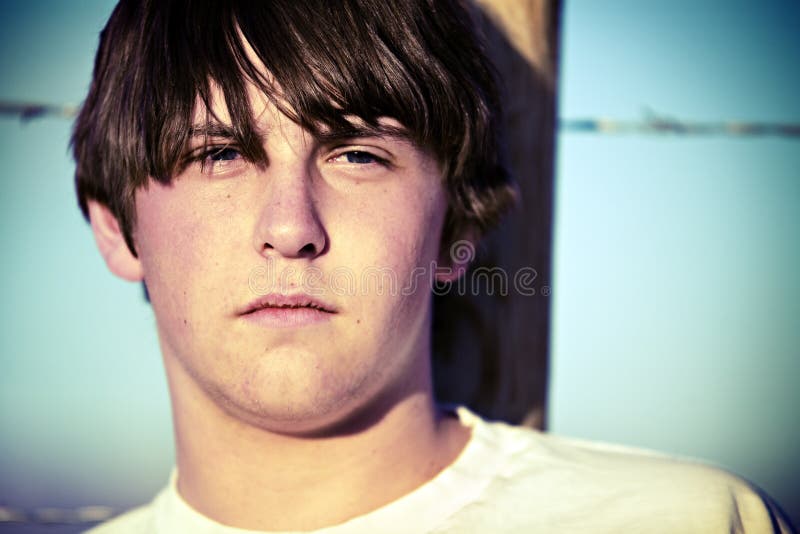 Teen boy portrait closeup against rural fence, cross-processed. Teen boy portrait closeup against rural fence, cross-processed