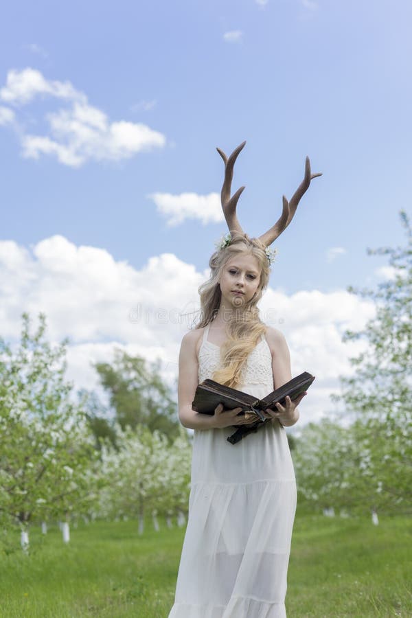 Teen beautiful blonde girl wearing white dress with deer horns o