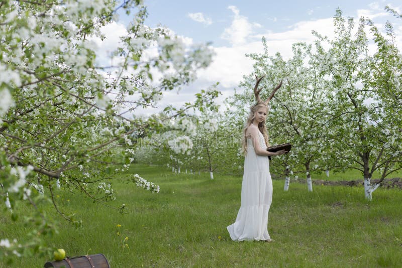 Teen beautiful blonde girl wearing white dress with deer horns o