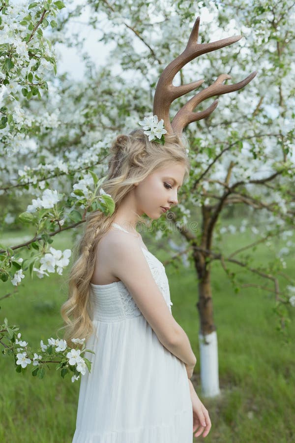 Teen beautiful blonde girl wearing white dress with deer horns o