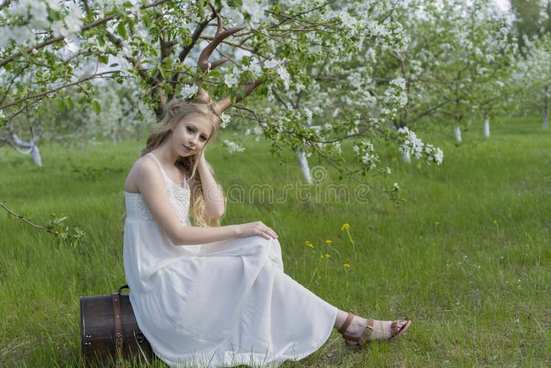 Teen beautiful blonde girl wearing white dress with deer horns o