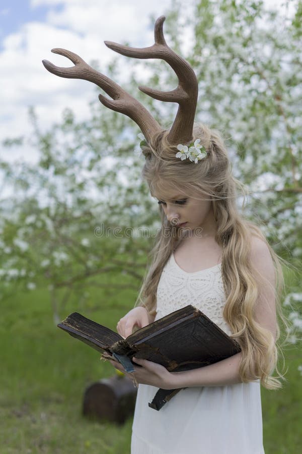 Teen beautiful blonde girl wearing white dress with deer horns o