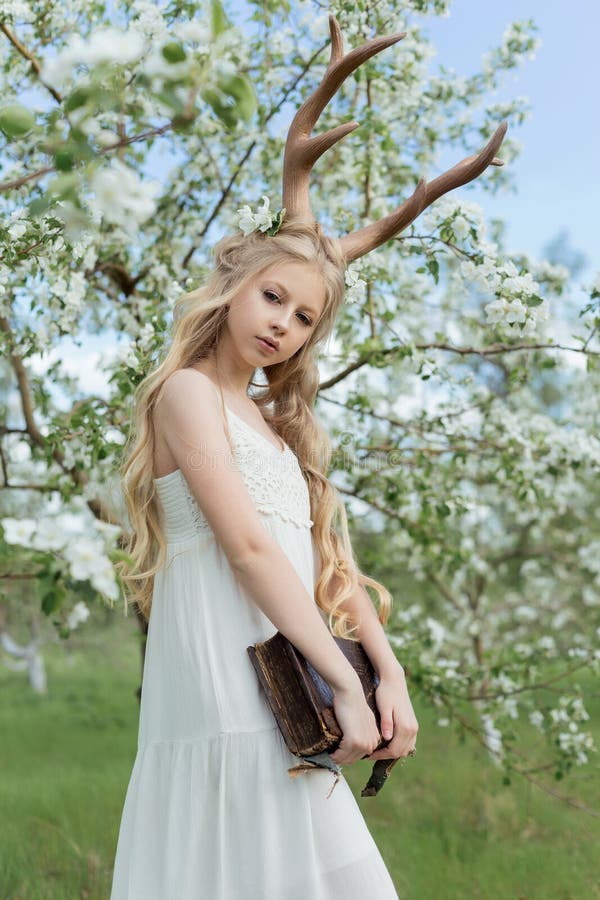 Teen beautiful blonde girl wearing white dress with deer horns o
