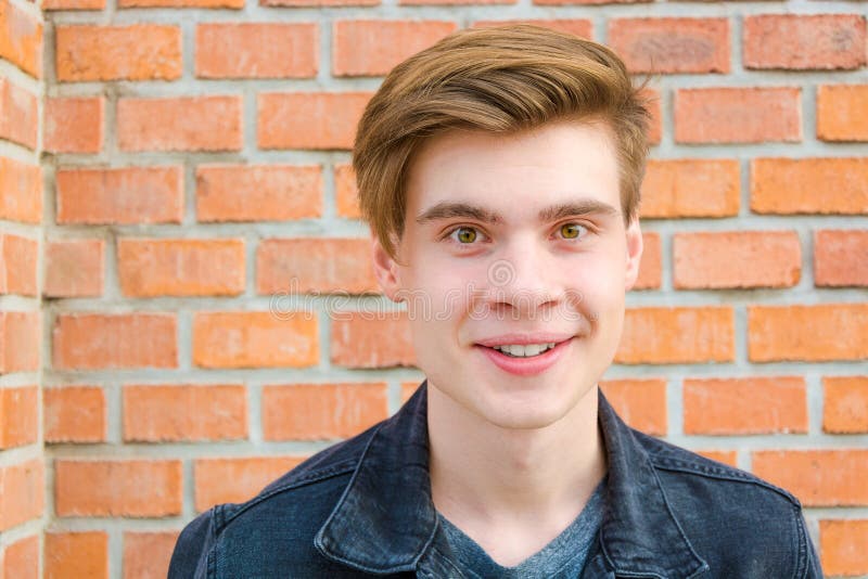 Happy excited teen boy portrait with big smile on his face, posing over red brick wall contrast. Happy excited teen boy portrait with big smile on his face, posing over red brick wall contrast